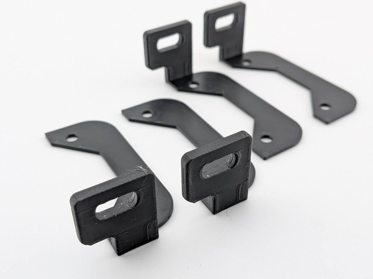 Angled product-only view of four Black ABS horizontal amplifier mounting feet showing the slots and mounting holes