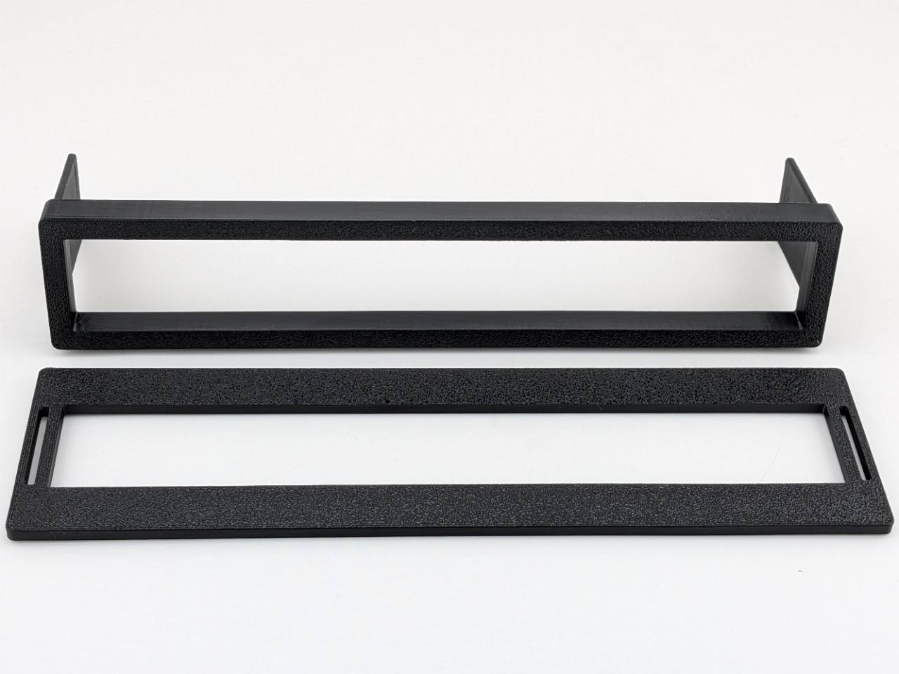 Black example of the two TightPrints replacement pieces included with one order, faceplate and fitment-based bezel; equalizer is not included