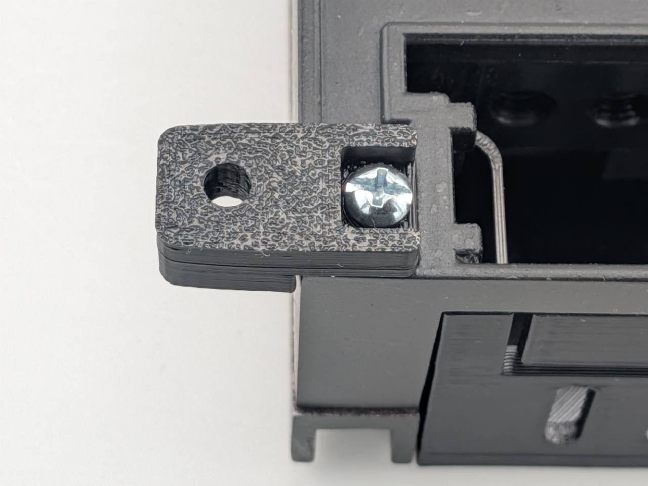 Close-up of a silver amplifier-attachment screw securing a Black TightPrints mounting foot; amplifier and TightPrints detachable plate shown for fitment only and not included