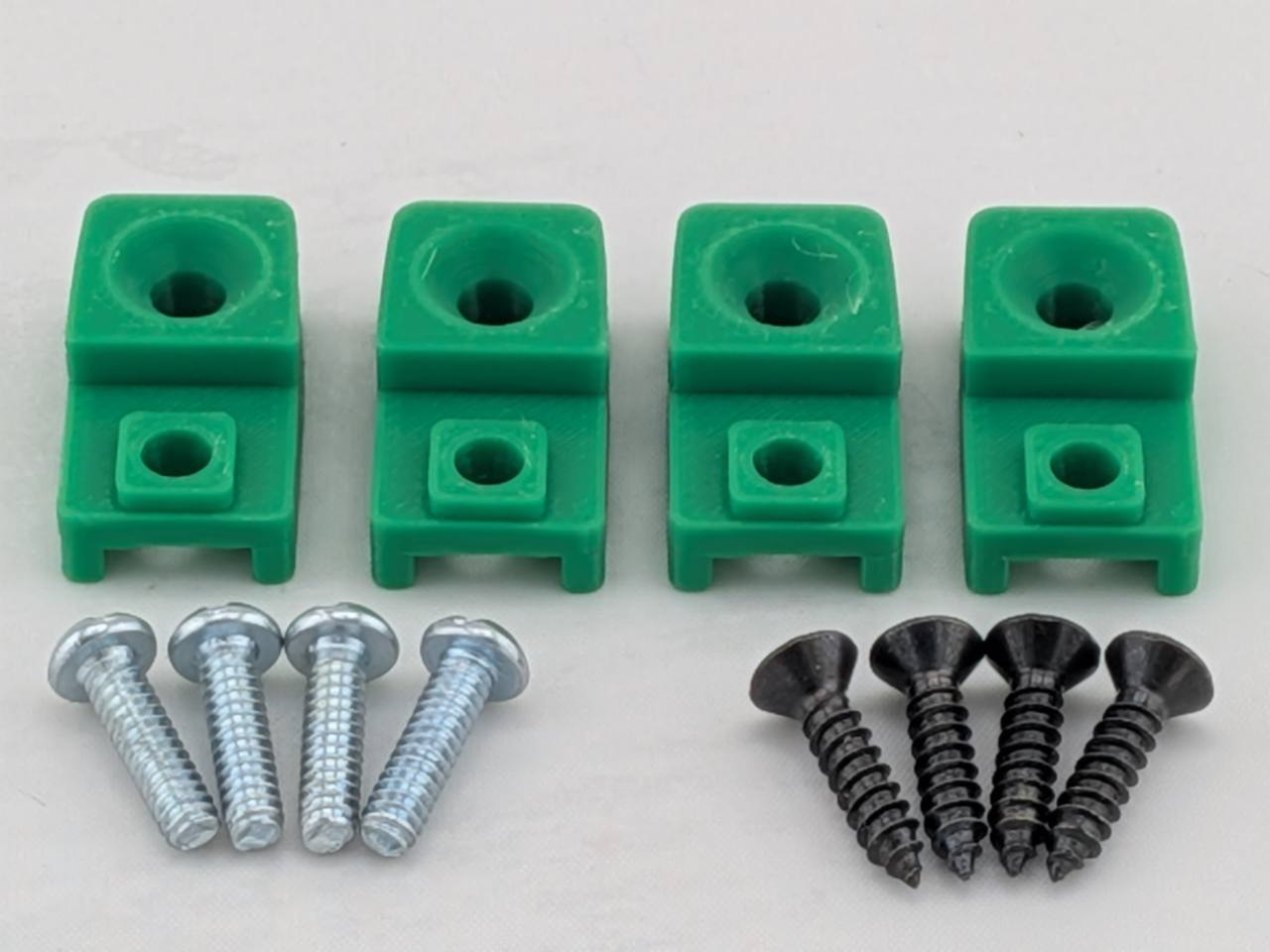 Green TightPrints replacement amplifier mounting feet kit for compatible Kicker Stillwater Designs amplifiers, showing four feet and eight included screws