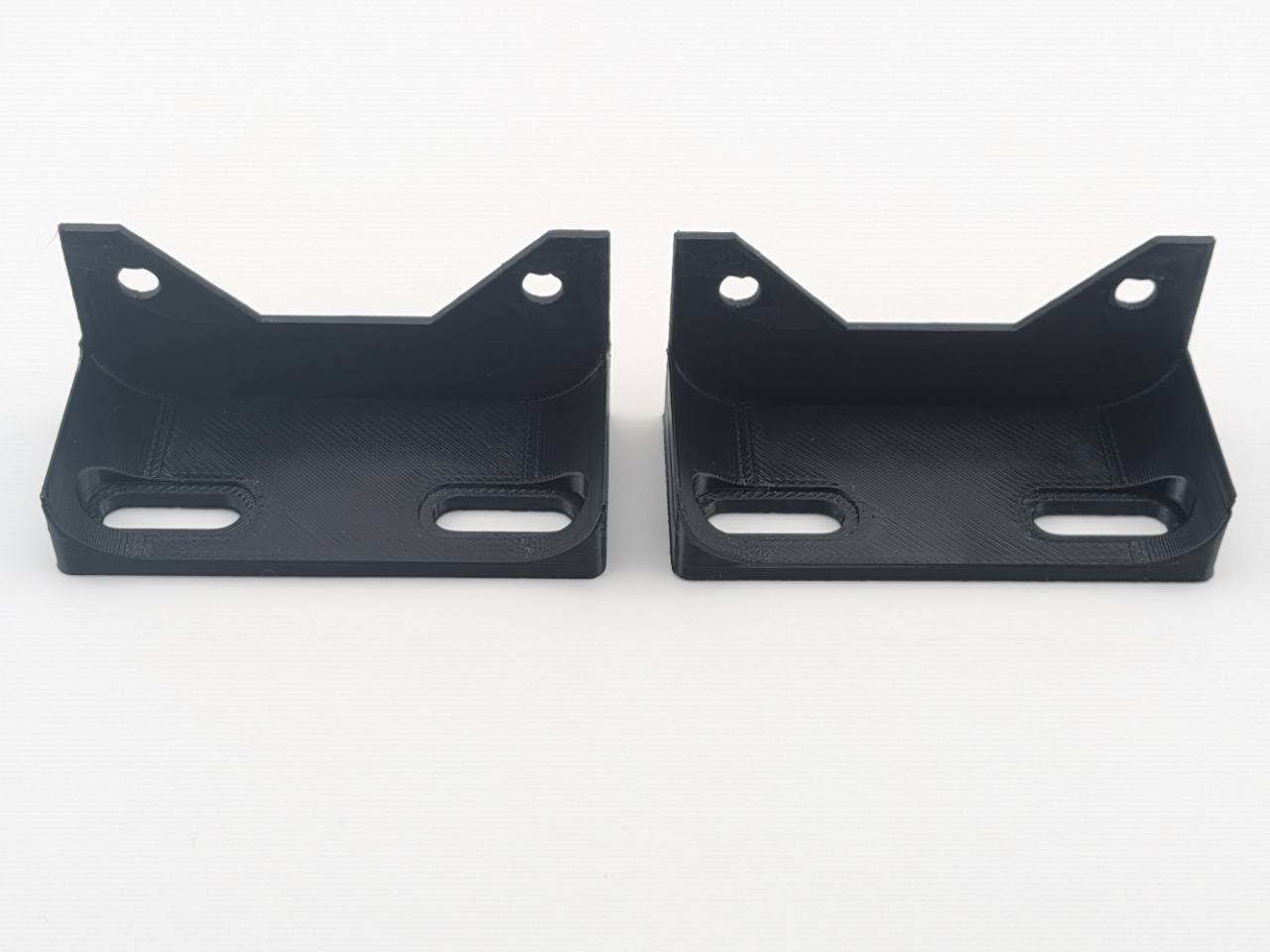 Two Black TightPrints vertical amplifier mounting feet viewed from the front, showing the amplifier attachment holes and mounting-surface slots