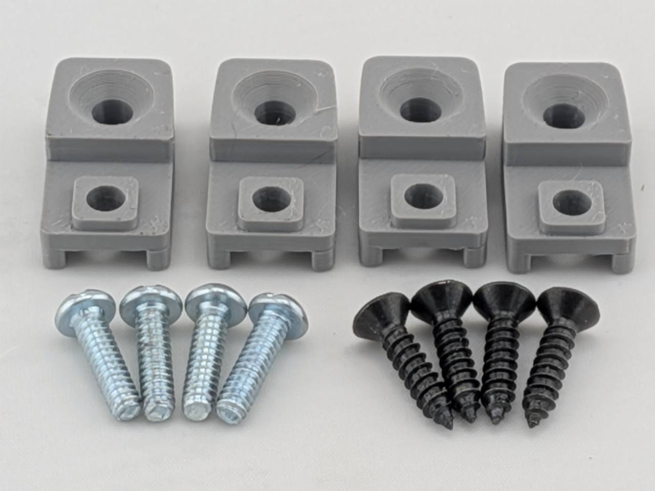 Gray TightPrints replacement amplifier mounting feet kit for compatible Kicker Stillwater Designs amplifiers, showing four feet and eight included screws