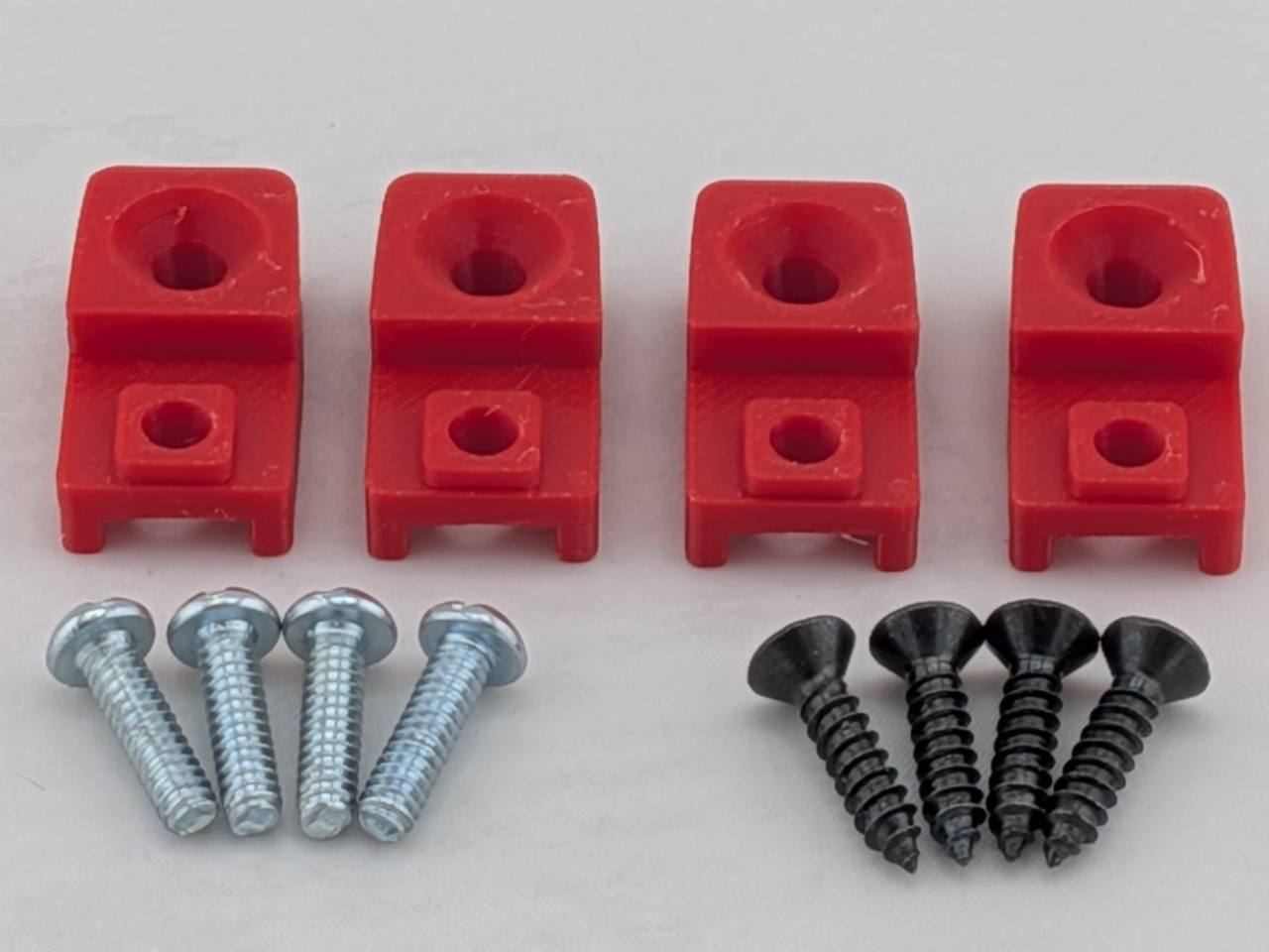 Red TightPrints replacement amplifier mounting feet kit for compatible Kicker Stillwater Designs amplifiers, showing four feet and eight included screws